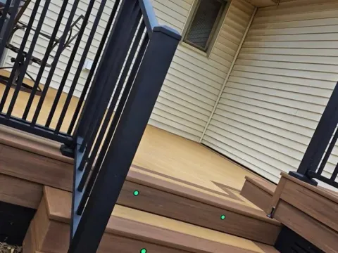 Two-tone composite deck and steps with step lights and a black metal railing