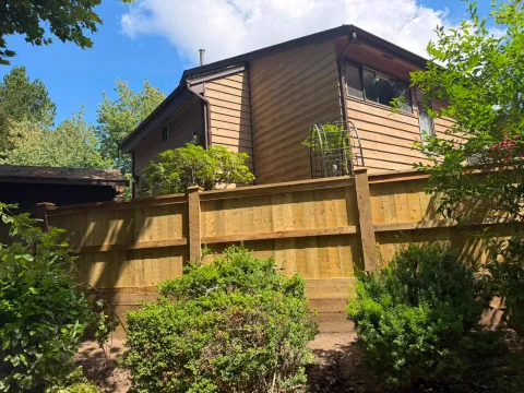 Tall wood privacy fence with capped posts in front of a two-storey house